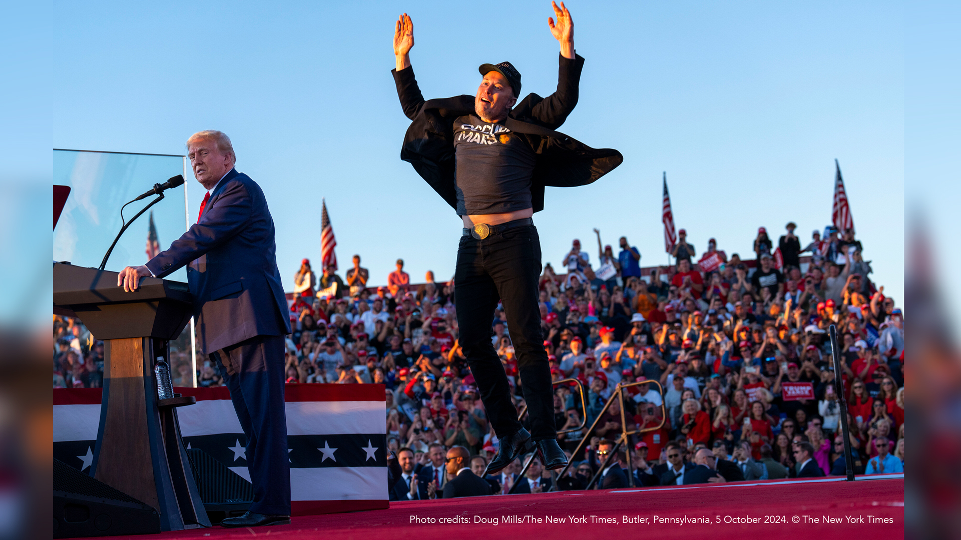 Trump talking on stage and Elon Musk jumping behind him