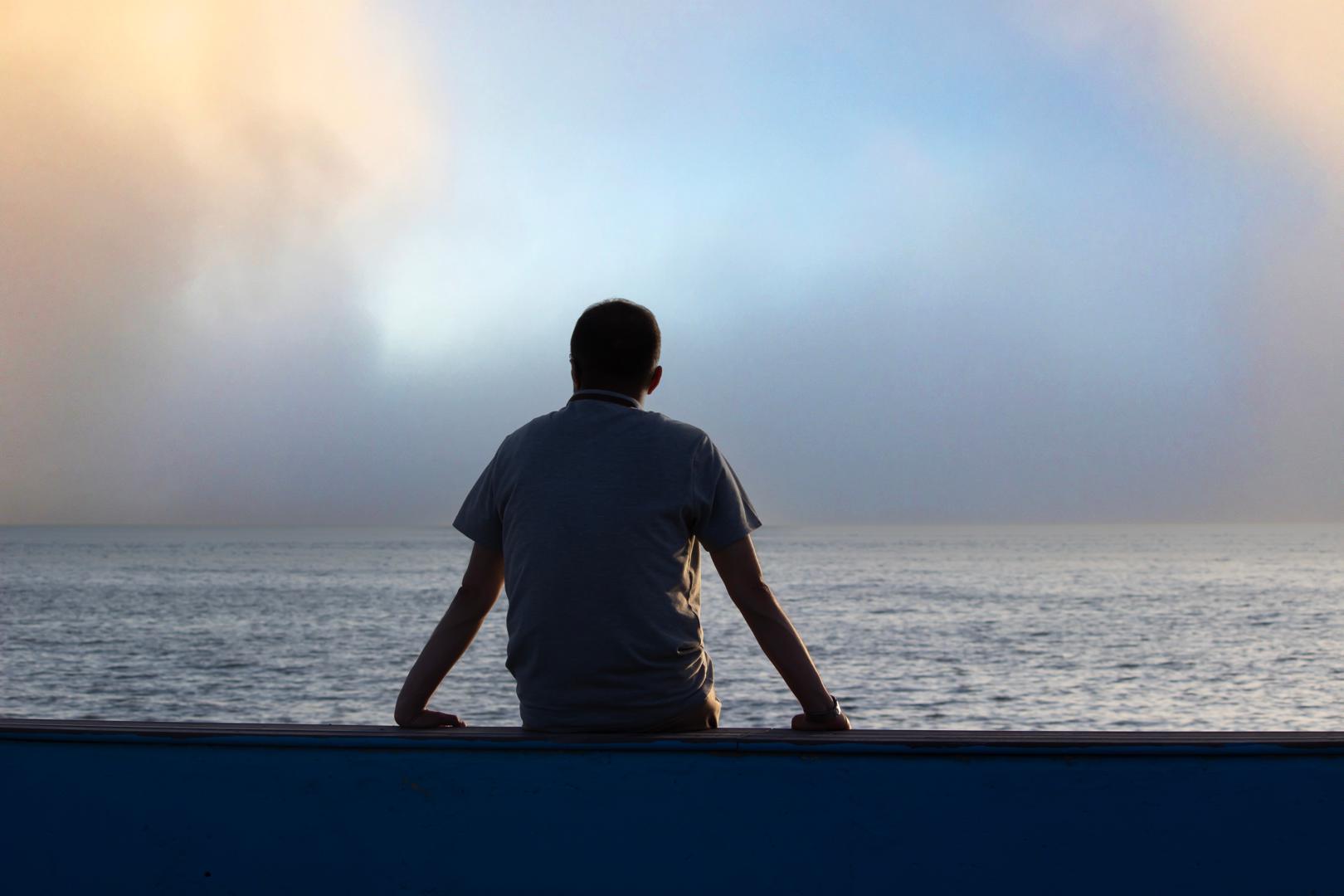 man sitting in front of sea